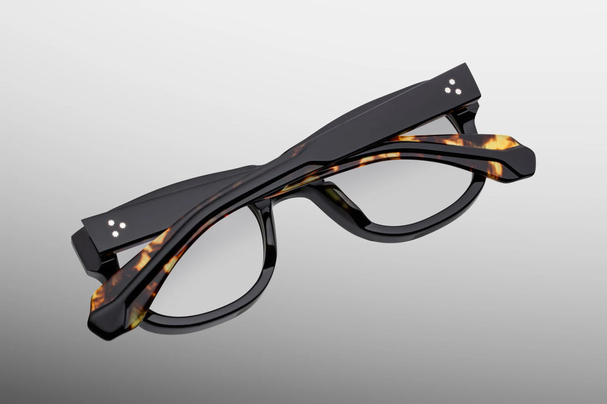 Close-up interior detail shot of the Jacques Marie Mage Amilcar RX Noir frames. The inner frame architecture reveals 10k gold spur-shaped rivet heads alongside detailed metalwork. Distinctive text foil-stamped in gold on the inner temple arm indicates the rare limited-edition serial number out of the global batch and the official "Handcrafted in Japan" production text. Available at WINK Optometrists