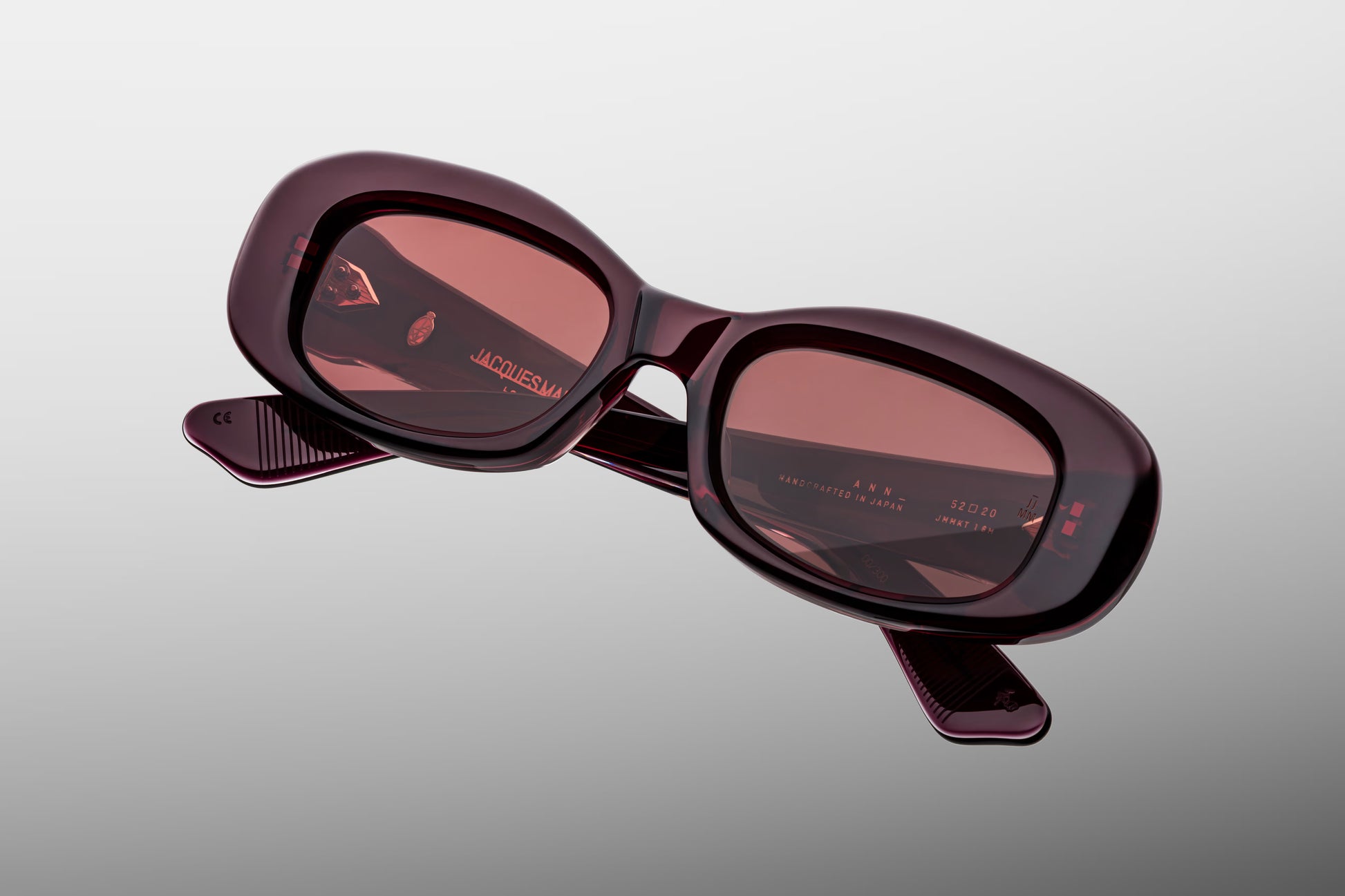 Close-up front detail of Jacques Marie Mage Ann Amarena frame showing spur-shaped rivets, bevelled edges and polished red acetate finish
Macro front view of JMM Ann Amarena sunglasses highlighting rectangular lens shape and handcrafted detailing