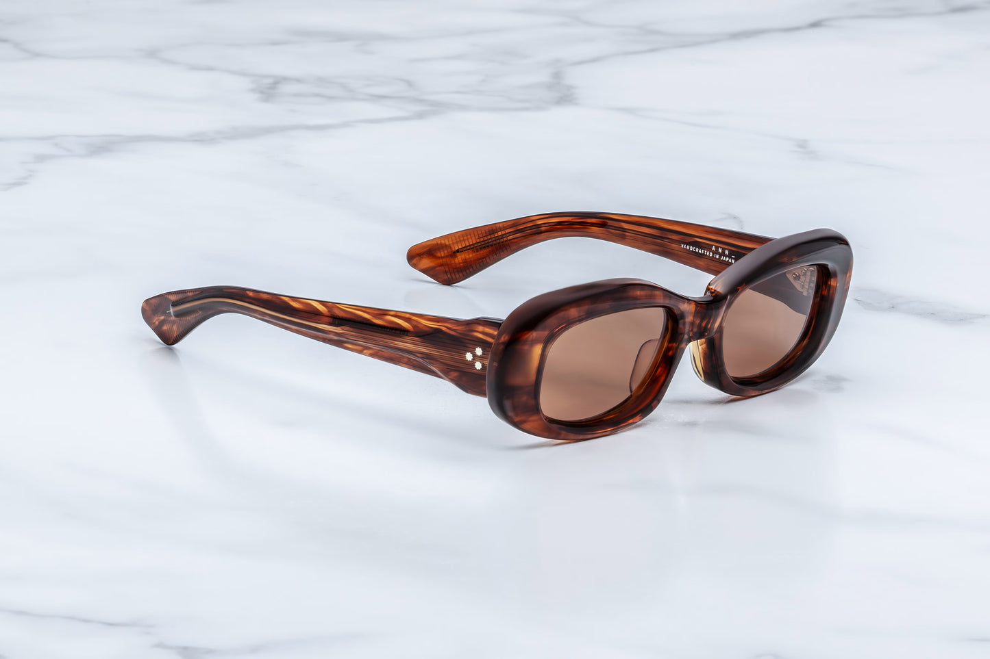 Jacques Marie Mage Ann Bourbon side view showing thick havana acetate temples, exposed wirecore and custom 7-barrel hinge detail
Side profile of JMM Ann Bourbon sunglasses highlighting sculpted 90s-inspired frame and premium acetate construction