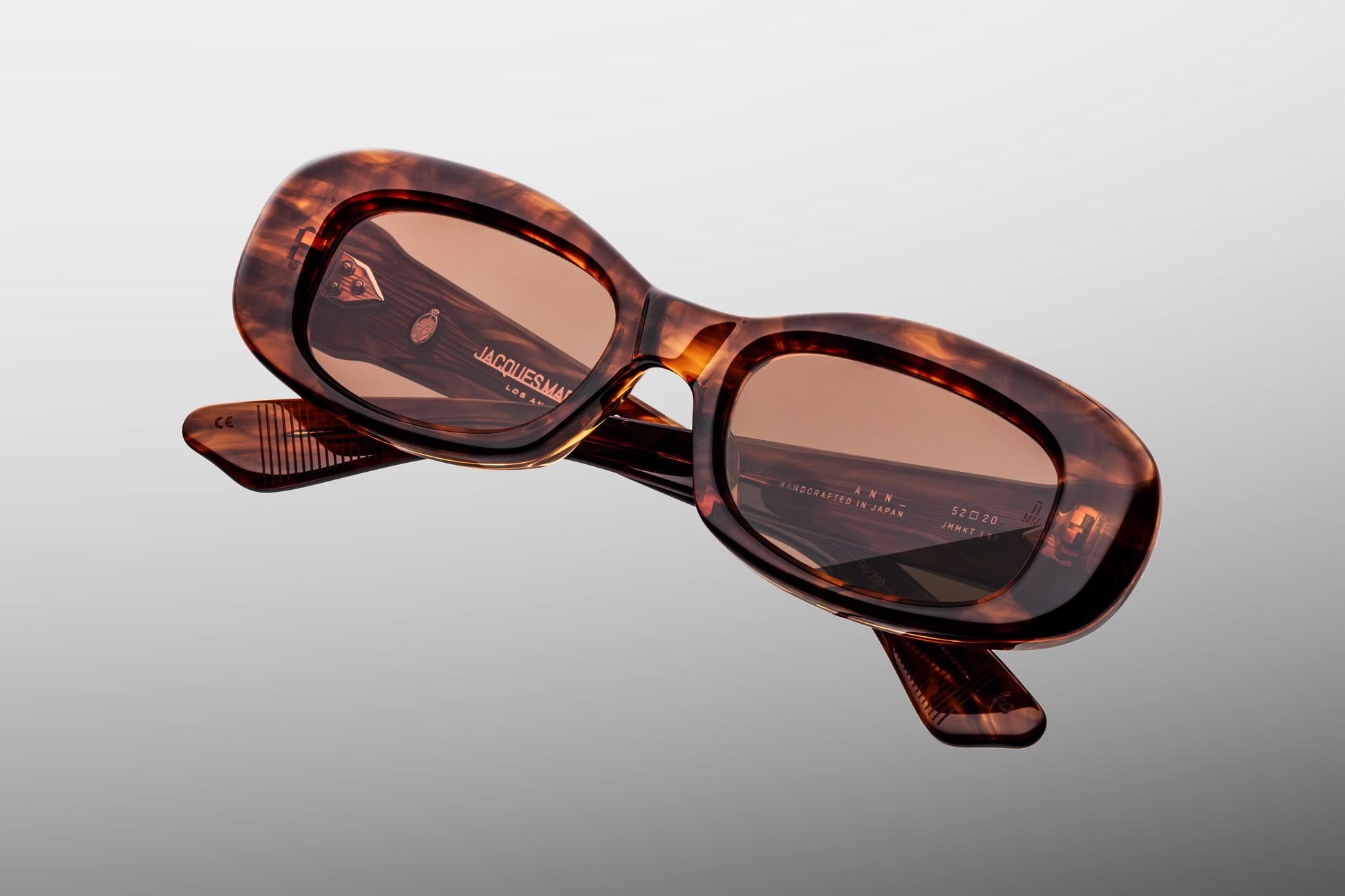 Close-up front detail of Jacques Marie Mage Ann Bourbon frame showing spur-shaped rivets, bevelled edges and polished tortoise acetate finish
Macro front view of JMM Ann Bourbon sunglasses highlighting rectangular lens shape and handcrafted detailing