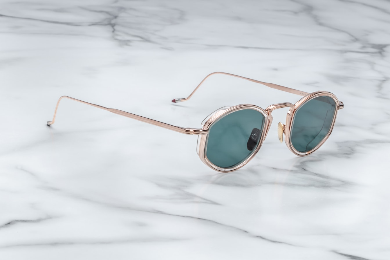Distinguished titanium spectacles with soft lens shape, featuring a distinct acetate rim insert, unique bridge construction, and hand-painted epoxy temple tips.
ROSE GOLD 100% BETA TITANIUM FRAME WITH PINK CURED CELLULOSE ACETATE INSERTS AND GREEN LENSES.
Limited production of 100 pieces. Handcrafted in Japan. Size 47/26