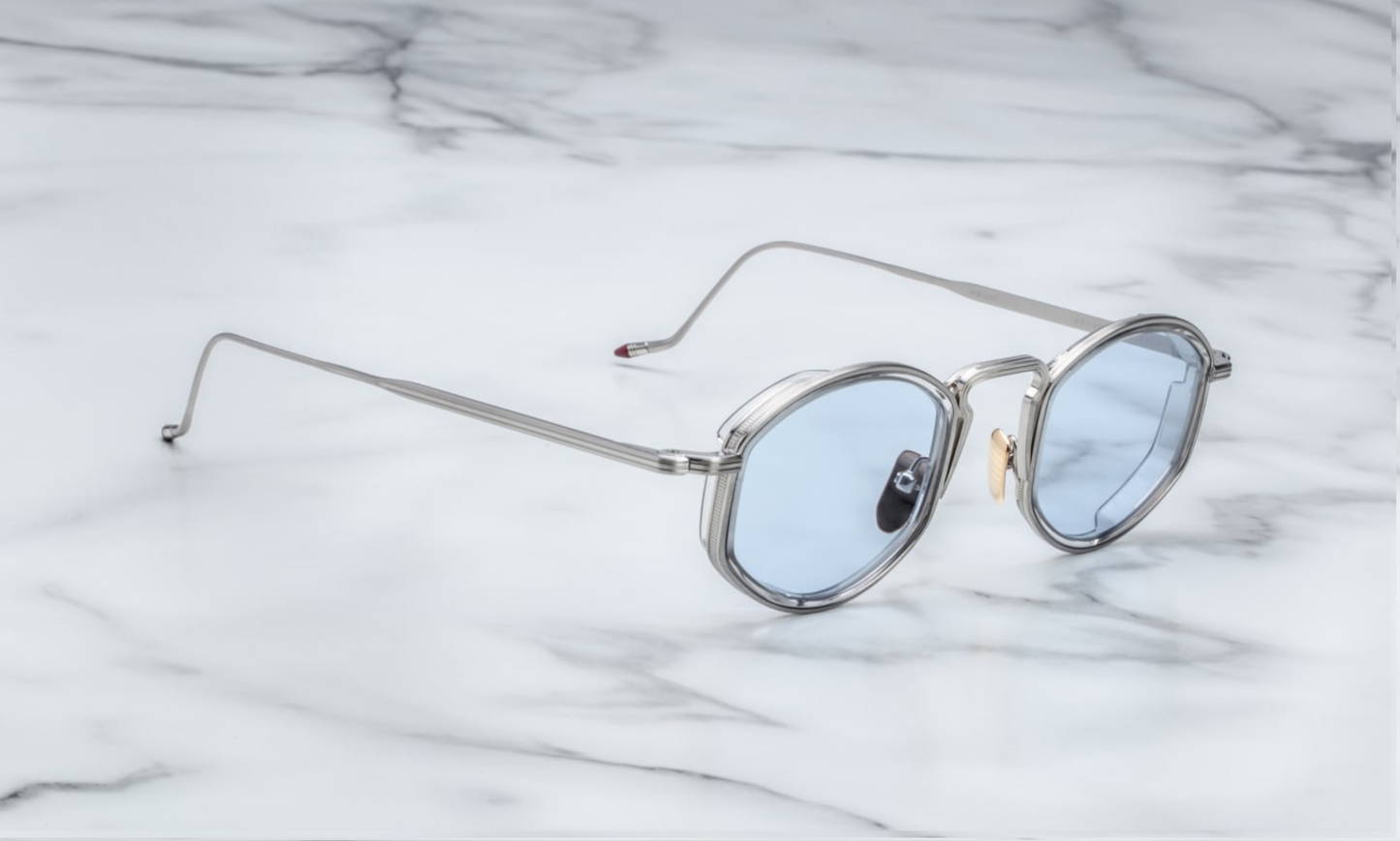 Much like the form of these distinguished double-nosed glasses, culture moves in kinks & curves & you along with it, banging against the abyss & confronting the absurd, a true intellectual army-of-one continuing in the tradition of French writer & Surrealist pioneer, Louis Aragon.
SILVER 100% BETA TITANIUM FRAME WITH GREY CURED CELLULOSE ACETATE INSERTS AND BLUE LENSES
Limited production of 200 pieces. Handcrafted in Japan. Size 47/26