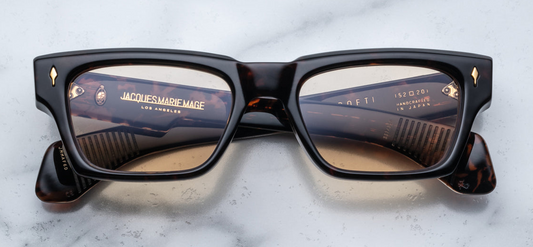  Jacques Marie Mage Ashcroft Agar sunglasses featuring a bold, rectangular frame crafted from 10mm polished havana tortoise cellulose acetate. The design includes sculpted double-laminated acetate temples with intricate Native American-inspired engravings along an exposed dark gold wirecore. The sunglasses are adorned with a signature dark gold arrowhead front pin and are equipped with yellow CR39 lenses offering 100% UV protection
