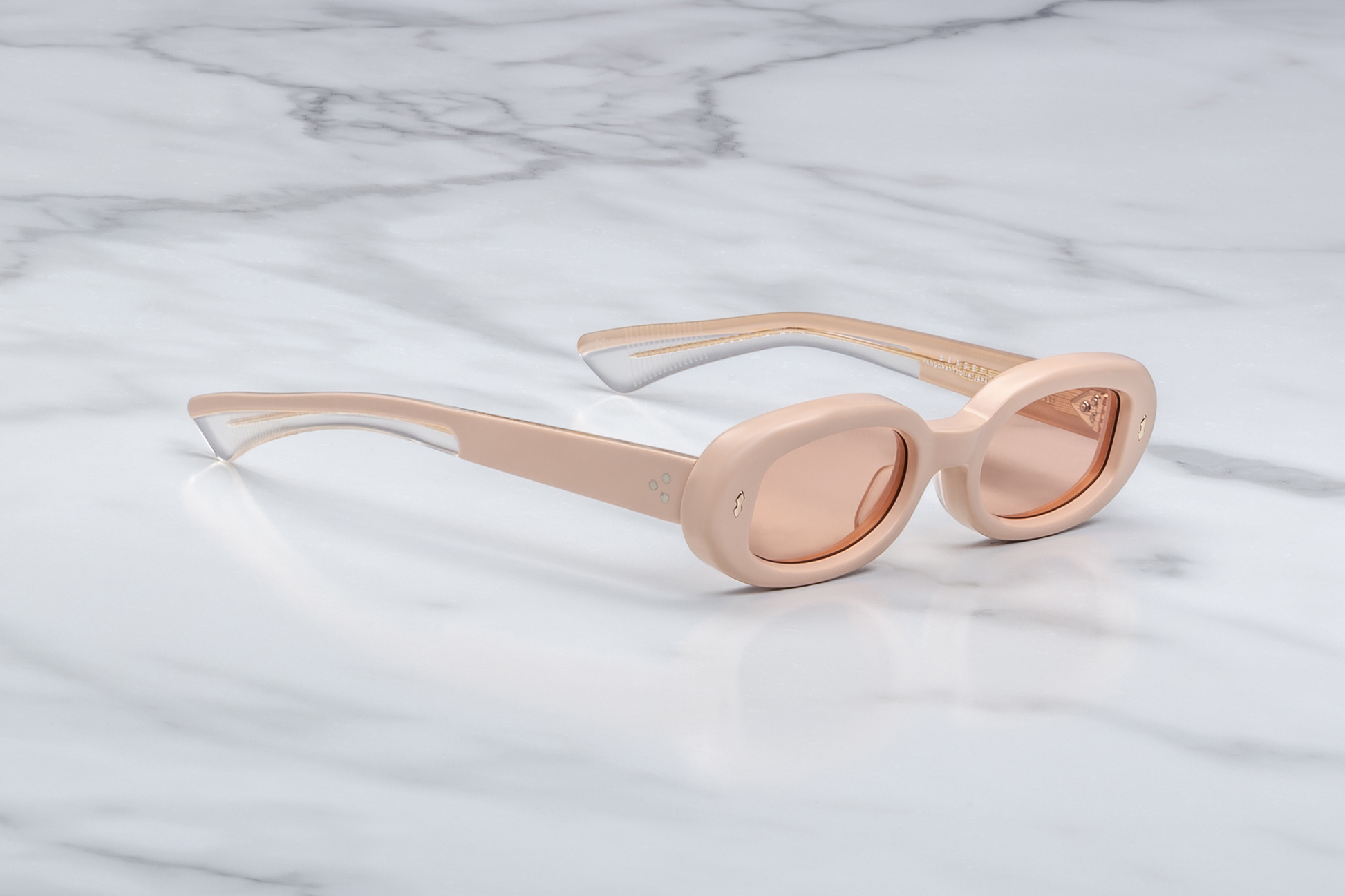 Close-up side view of Jacques Marie Mage Besset Dust Suede temple—8 mm cured matte orange‑peach cellulose acetate, light-gold arrowhead pin, light-gold lever wirecore, and tension‑secured 7‑barrel hairline‑engraved hinge.