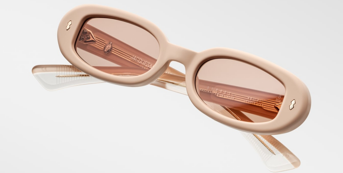 Angled downward view of Besset Dust Suede—matte suede‑textured peach frame with Marrakesh Armorlite lenses featuring backside anti‑reflective coating, oval ’90s silhouette, limited‑edition micro‑production of 50.