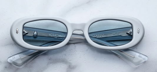 Front view of Jacques Marie Mage Besset Suede sunglasses in matte pastel blue acetate. Oval, ’90s‑inspired frames with silver wirecore and arrow‑head pin detail.