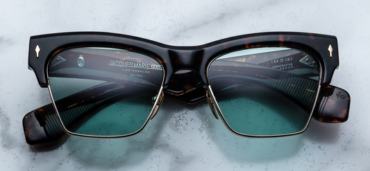 Front view of Jacques Marie Mage Bugsy Beau—mid‑century clubmaster sunglasses featuring light‑gold beta titanium rim with sculptural Havana acetate brow, turquoise CR‑39 lenses, and signature arrowhead front pins.