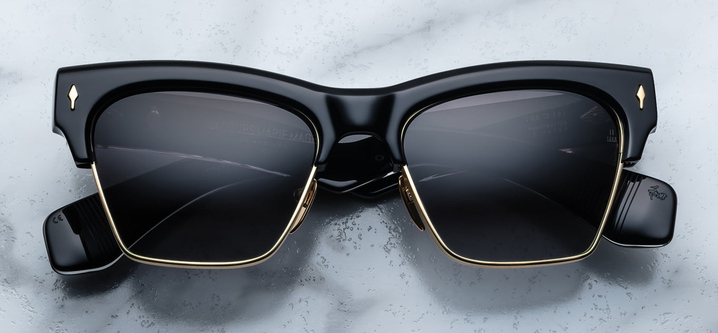 Front view of Jacques Marie Mage Bugsy Eclipse 2 sunglasses—mid‑century clubmaster style with dark‑gold beta titanium rim, thick black cured acetate brow, jet gradient CR‑39 lenses, and signature dark‑gold arrowhead front pin.