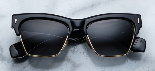 Front view of Jacques Marie Mage Bugsy Eclipse 2 sunglasses—mid‑century clubmaster style with dark‑gold beta titanium rim, thick black cured acetate brow, jet gradient CR‑39 lenses, and signature dark‑gold arrowhead front pin.