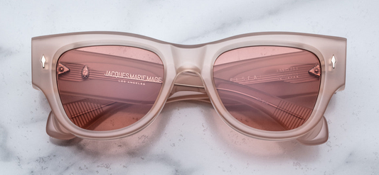 Front view of Jacques Marie Mage Chelsea sunglasses in Pink Quartz—oversized soft Panto frames handcrafted from 10mm double-laminated pink cellulose acetate. Features include sterling silver arrowhead front pin, exposed cantilever wirecore, and custom 7-barrel hairline hinge. Autumn gradient CR39 lenses with backside anti-reflective treatment provide 100% UV protection. Limited edition of 250 pieces, handcrafted in Japan.