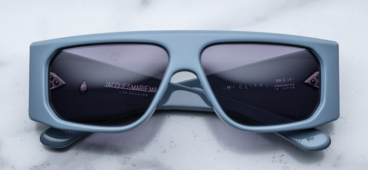 Front view of Jacques Marie Mage Cliff Tiger sunglasses, featuring a bold, square frame in a rich, swirled Tiger acetate pattern with shades of amber, brown, and black. The frame has a striking visual depth, with the natural variations in the acetate adding a unique, luxurious touch. The dark lenses enhance the sophisticated and refined design of the sunglasses