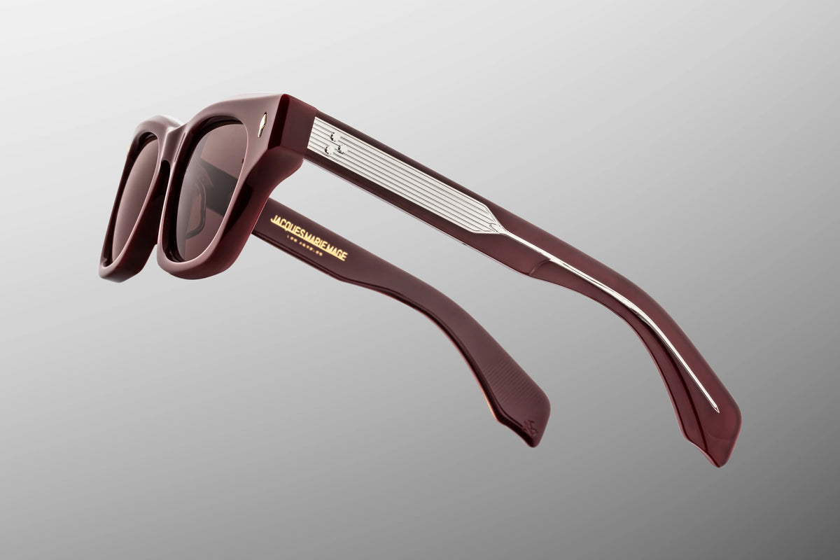  Side profile view of the Jacques Marie Mage Dealan in Bordeaux Empire. The focus is on the thick, sculptural paddle temple arms crafted from premium cassis red acetate. A high-shine silver palladium tension-secured 7-barrel hinge seamlessly anchors the side arms to the deep burgundy frame face. Available at WINK Optometrists.