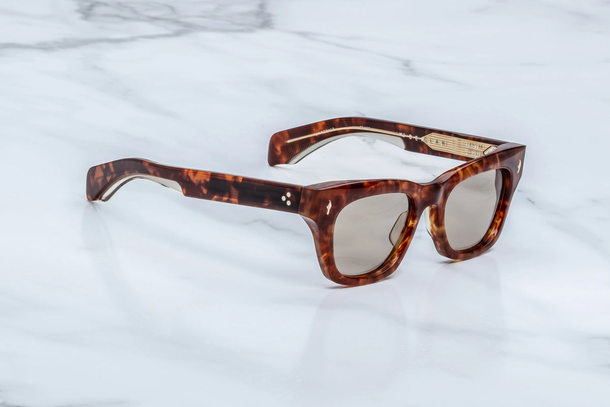 Side profile view of the Jacques Marie Mage Dealan 50/20 sunglasses. The thick, custom double-laminated tortoiseshell acetate temple arms measure 142mm in length and extend straight back, tapering cleanly toward the curved ear pieces, highlighting the highly polished, glossy finish of the honey-toned frame.