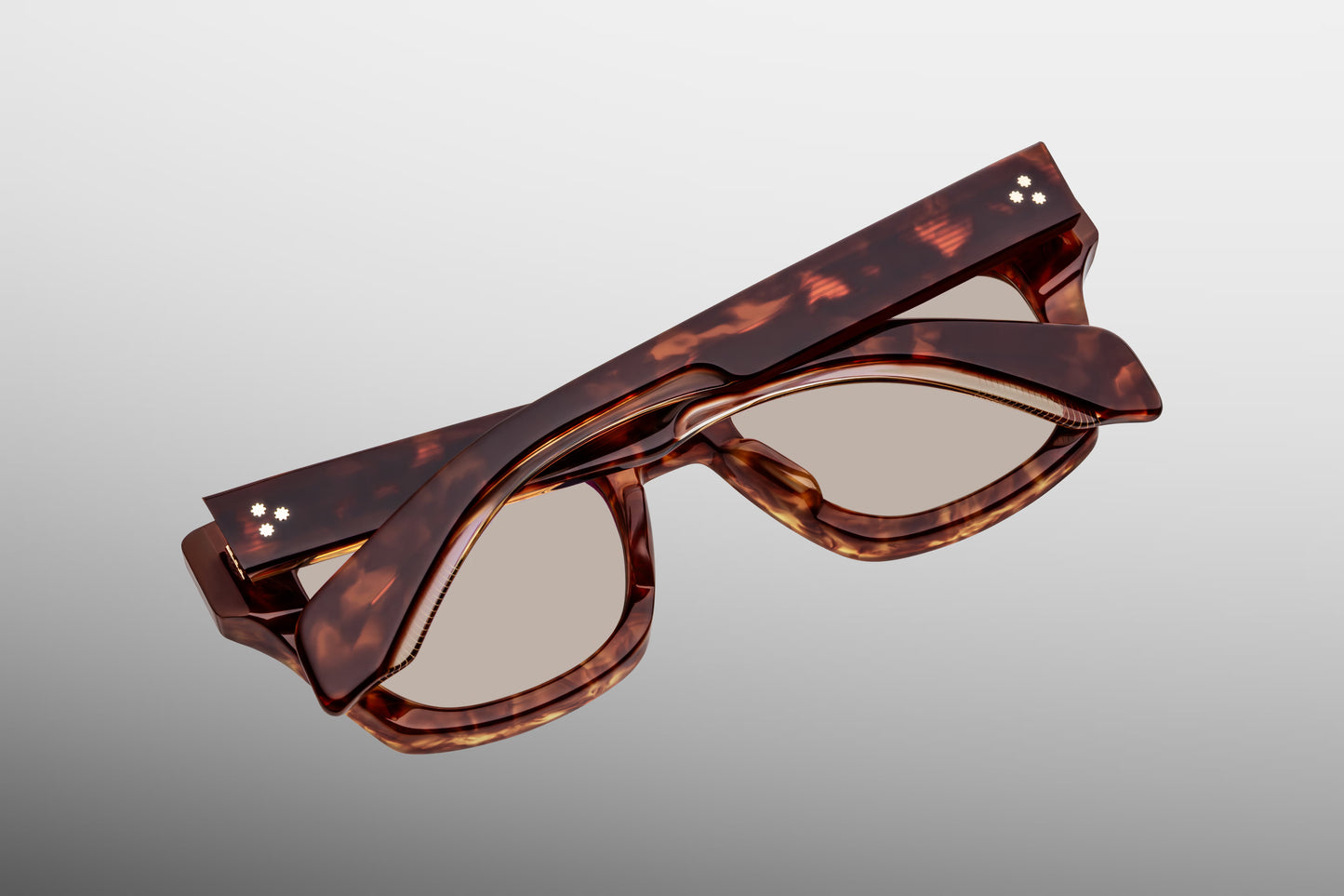 Close-up from the back of Jacques Marie Mage Dealan 53 Honeycomb sunglasses, showcasing the inner side-temple serial number stamping, the sterling silver tension-secured 7-barrel hinge, and the backside anti-reflective coating on the solid tint lenses