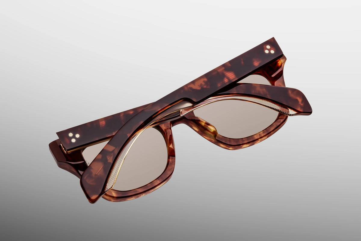 Detailed close-up view from behind the hinge of the JMM Dealan 50/20 sunglasses. The shot reveals the interior sizing engraving "50 x 20" alongside a heavy-duty, tension-secured custom 7-barrel hinge in light gold that anchors the temple arm to the compact frame chassis.
