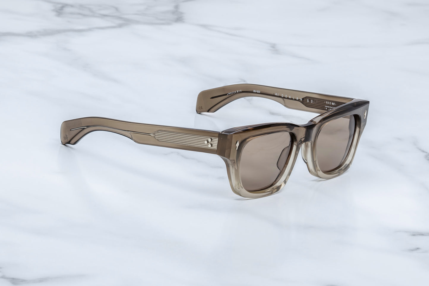 Three-quarter angle of Jacques Marie Mage Lescot sunglasses, showing the thick sculptural acetate beveling and the transition from the dark grey-brown front frame to the wide temples.