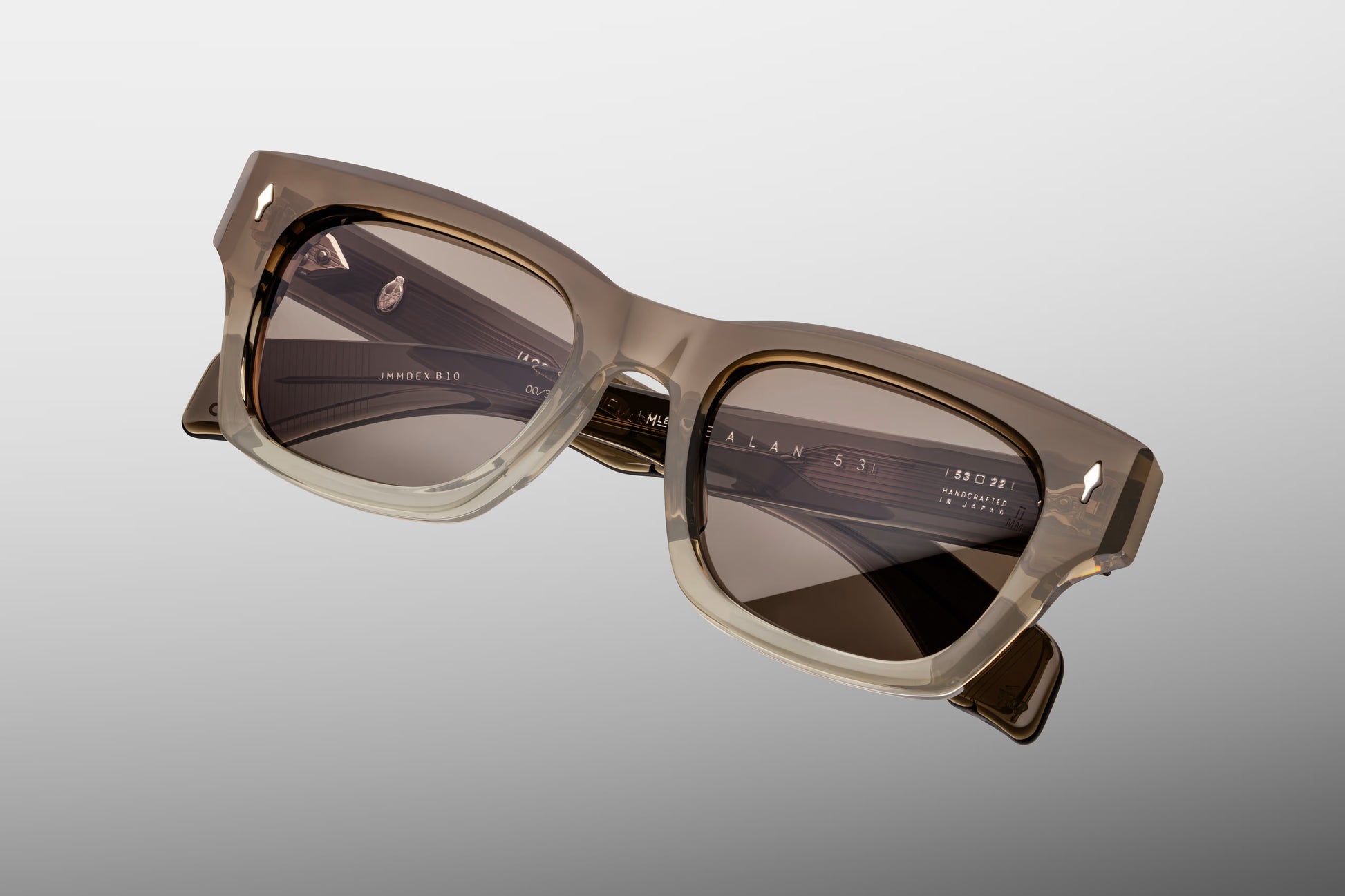 Top-down macro shot of Jacques Marie Mage Lescot sunglasses, highlighting the substantial 10mm thickness of the dark charcoal acetate frame and the precision-engineered silver metal hardware.