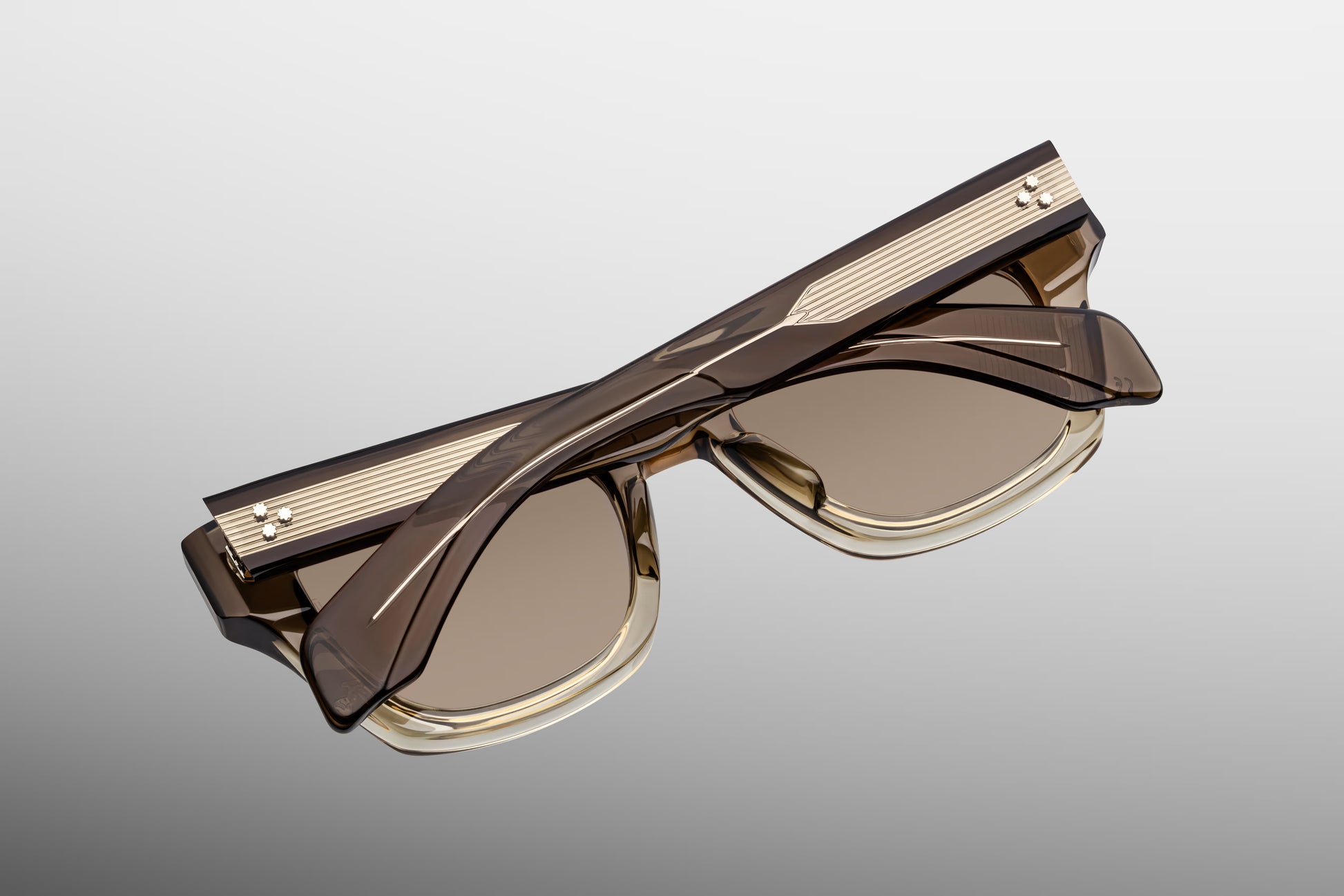 Close-up from the back of Jacques Marie Mage Lescot sunglasses, showcasing the inner side-temple limited-edition serial number stamping, the custom silver 9-barrel hinge, and the brass-coloured lenses.