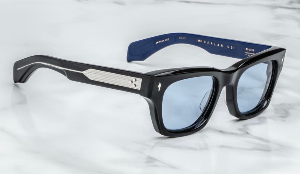 Side view A bold, square Jacques Marie Mage Dealan frame in the "Sienne" colorway—crafted from 10 mm black cured cellulose acetate,exposed sterling‑silver wire‑core temple detailing and double‑laminated acetate construction. JMM’s signature arrowhead metal inlays at the hinges and Cerulean CR39 100% UV lenses This medium-sized, ‘60s-inspired unisex frame is handcrafted in Japan in a limited batch, echoing mid‑1960s rock‑’n’-roll