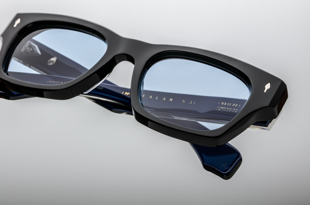 Side view A bold, square Jacques Marie Mage Dealan frame in the "Sienne" colorway—crafted from 10 mm black cured cellulose acetate,exposed sterling‑silver wire‑core temple detailing and double‑laminated acetate construction. JMM’s signature arrowhead metal inlays at the hinges and Cerulean CR39 100% UV lenses This medium-sized, ‘60s-inspired unisex frame is handcrafted in Japan in a limited batch, echoing mid‑1960s rock‑’n’-roll