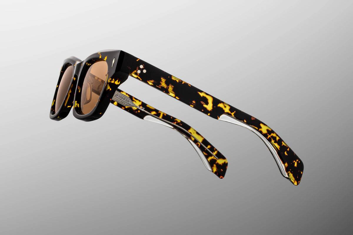ocused close-up of the temple arms of the Dealan Tokyo glasses. The shot highlights the custom hairline-engraved inner metal wirecore, which subtly reflects light through the rich, semi-translucent dark Havana tortoiseshell structure