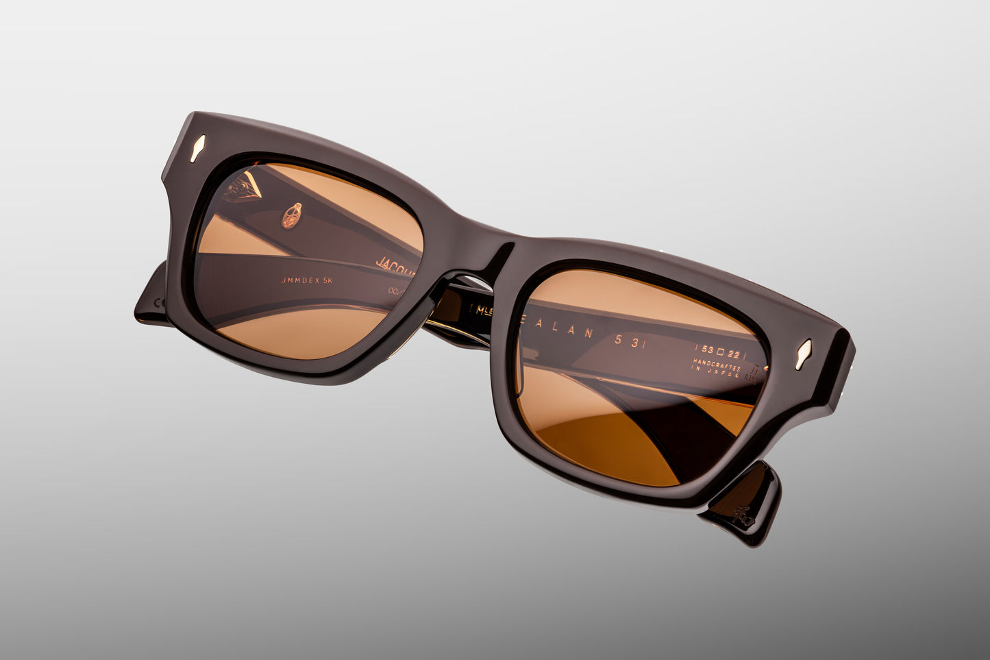 Top-down macro shot of Jacques Marie Mage Dealan 53 Walnut sunglasses, highlighting the substantial 10mm thickness of the brown acetate frame and the precision-engineered dark gold metal hardware.