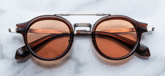 Front view of Jacques Marie Mage Delage Zoltar sunglasses—’50s‑inspired round combo spectacles with brown cured acetate rims, sterling‑silver beta‑titanium brow bar, engraved double nose bridges, copper CR‑39 lenses with AR coating, and limited‑edition design.