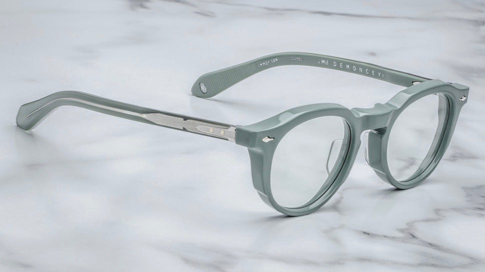 Close-up side view of Demoncey Breathe temple detailing superlight green cured acetate layered over silver wirecore, silver tension‑secured 7‑barrel hinge, and triple spur rivets for architectural accent