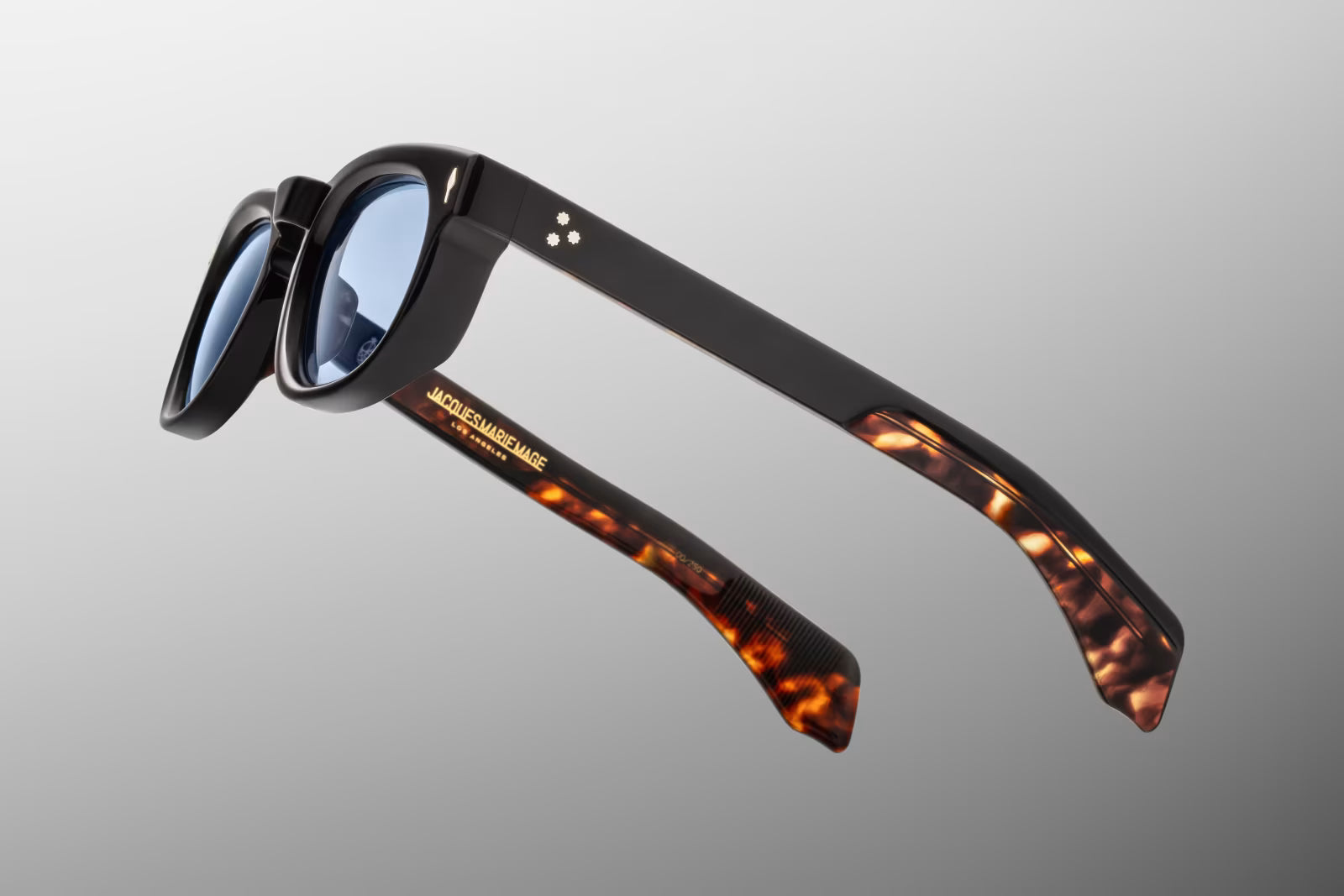 Side view of the JMM Pepper 10Y sunglasses temple arm, showcasing the glossy black outer frame, custom wirecore with Southwest-inspired hairline engravings, and a silver spur-shaped rivet
