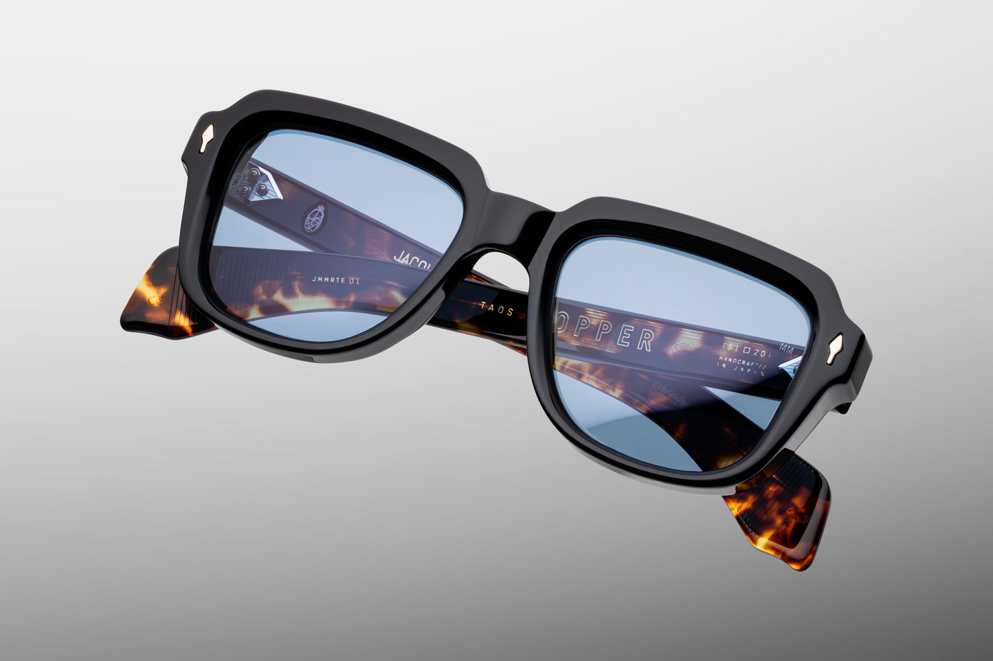 Top-down view of the JMM Taos 10Y Noir, revealing the frame’s wide, blocky geometry, the heavy 12mm thick black acetate brow line, and the tension-secured 7-barrel hinges finished in silver palladium