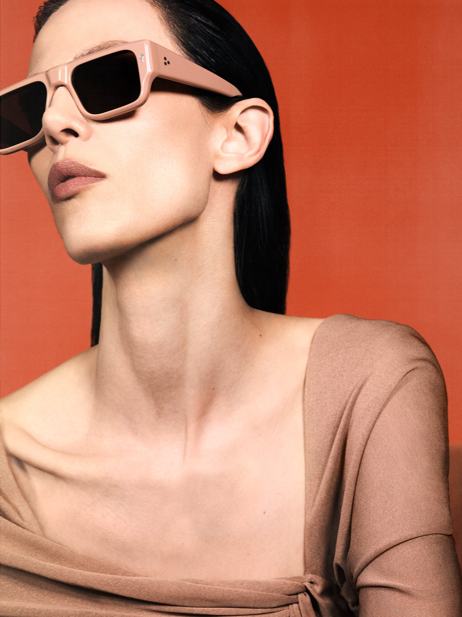 Model wearing Jacques Marie Mage Devoto Porter sunglasses — rectangular brown acetate frame with bold brow‑line, sienna‑brown lenses, profile view