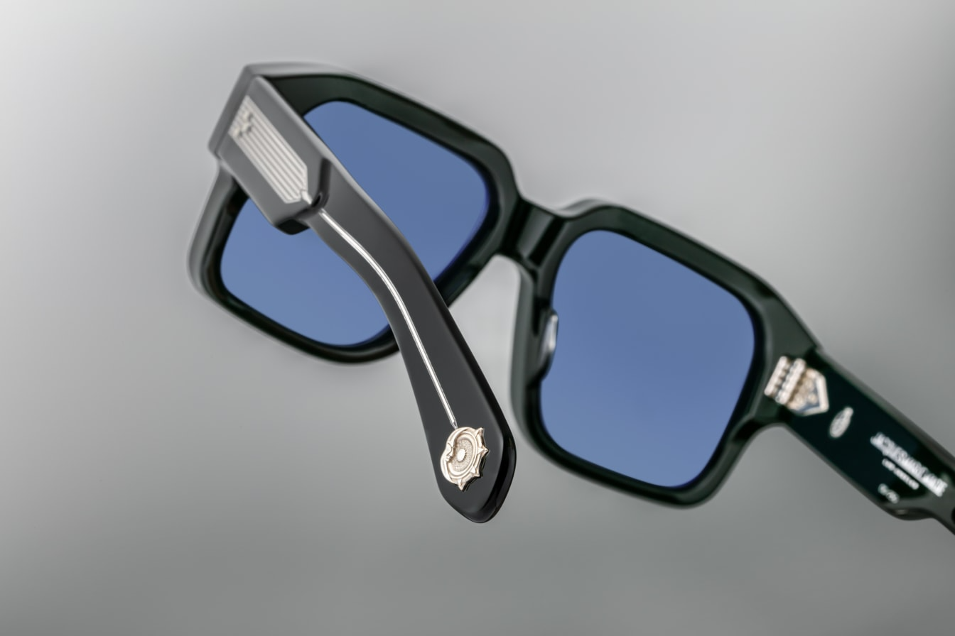 Back view of Jacques Marie Mage Donato Shadow sunglasses, revealing the smooth, matte Shadow acetate of the frame extending through the temples. The gold-tone metal detailing at the temple ends contrasts beautifully with the dark acetate, while Rossi’s signature symbol is subtly engraved, marking the sunglasses as a work of craftsmanship