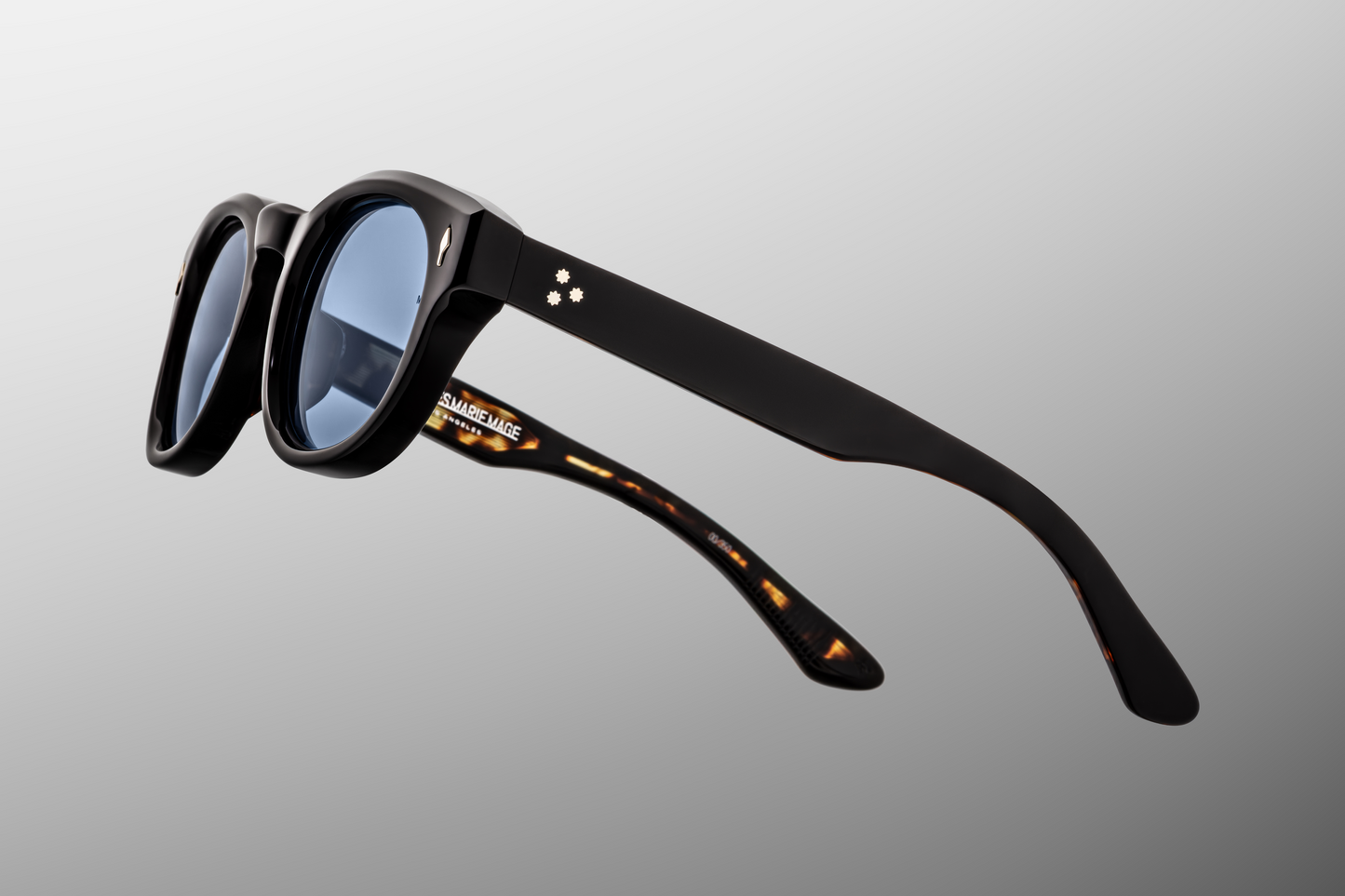 Close-up of the Dr. Dream Noir hinge — silver 7-barrel tension-secured hinge with hair-line detailing and spur rivet, set into dense black acetate.