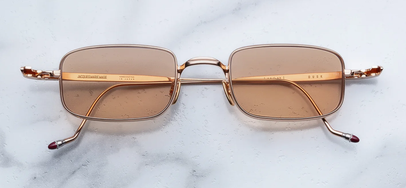 Front studio shot of Jacques Marie Mage Dusk sunglasses in Sweetheart, featuring a minimalist 1990s-style micro titanium frame in polished rose gold with Mode Orange lenses and a sleek single bridge
