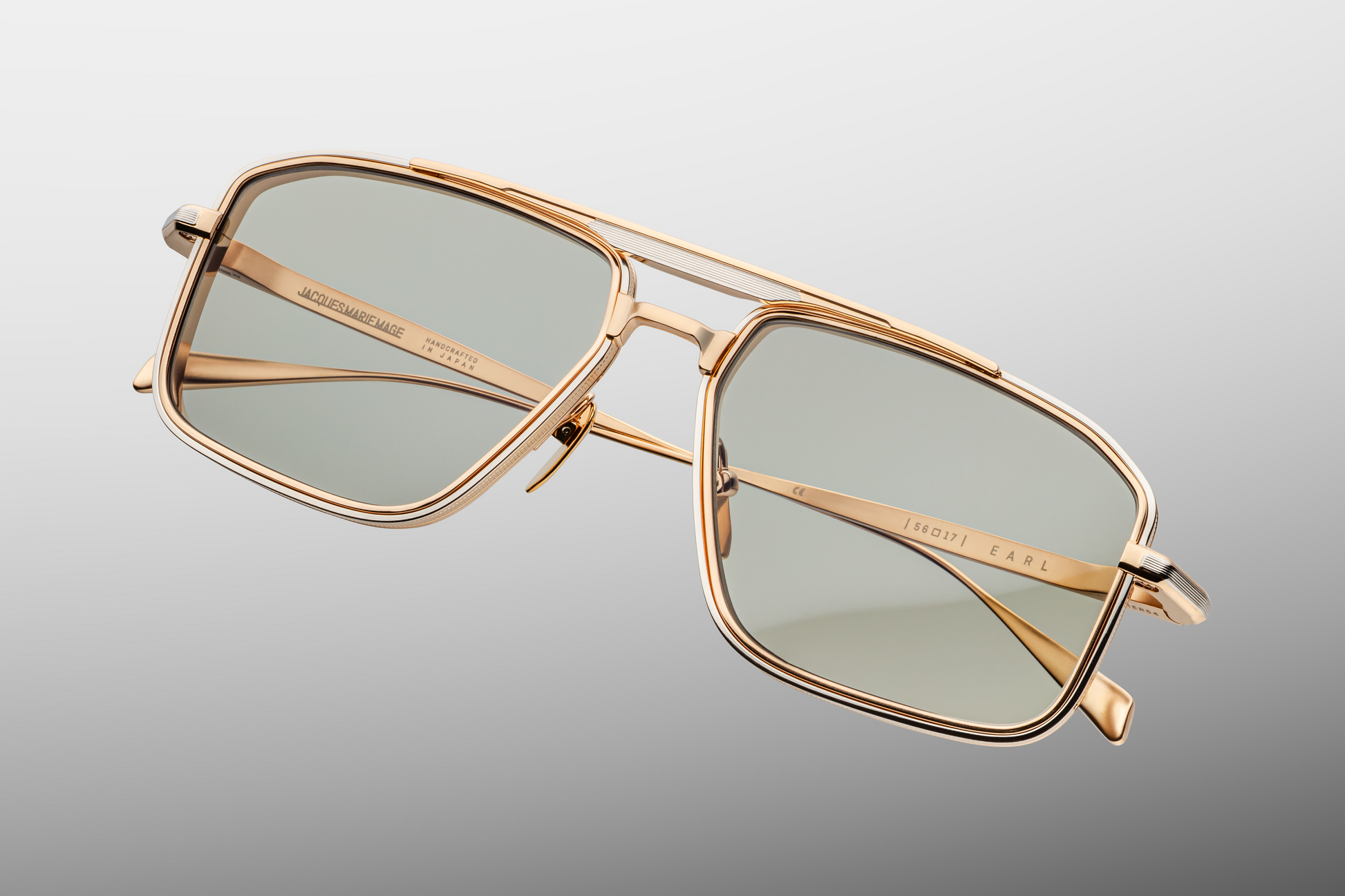 Top-down view of Jacques Marie Mage Earl Altan sunglasses: sleek navigator silhouette with dual-tone brow and temple detailing, 4mm titanium lens-rim inserts, and mist CR39 lenses. Limited edition of 500 pieces, handcrafted in Japan