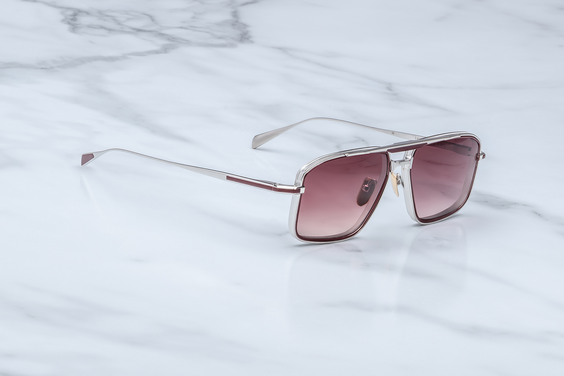 Side view of Jacques Marie Mage Earl Bordeaux sunglasses: handcrafted 100% titanium frame with Bordeaux eyerim inserts, sterling silver temples, and mahogany gradient CR39 lenses. Features include a monoblock hinge, adjustable titanium nose pads, and grooved temple tips. Limited production batch of 400 pieces, handcrafted in Japan