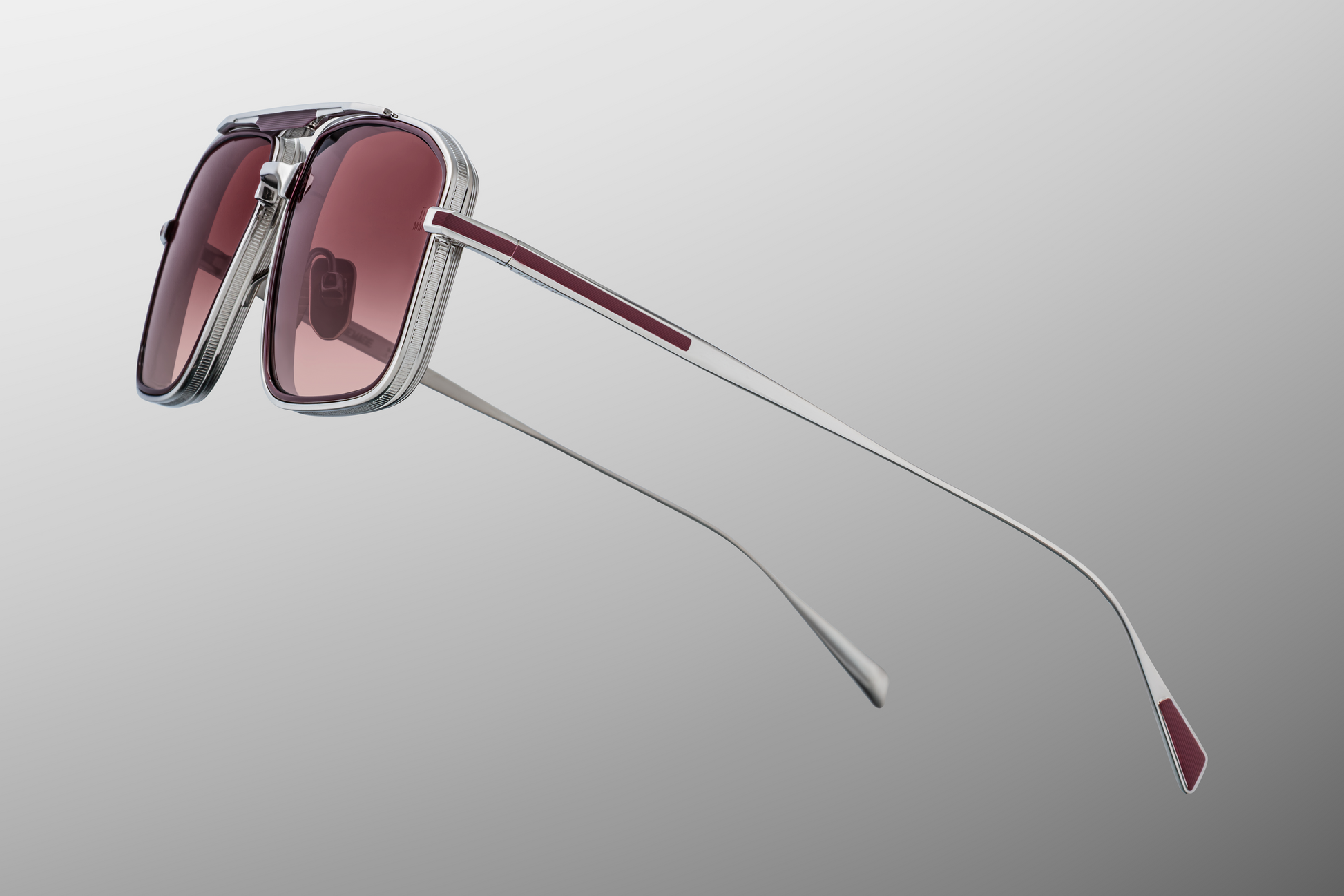 Close-up of Earl Bordeaux temple showing silver hairline-engraved beta titanium structure, hidden tension-secured hinge, custom logo nose pad detail, and sleek acetate tips