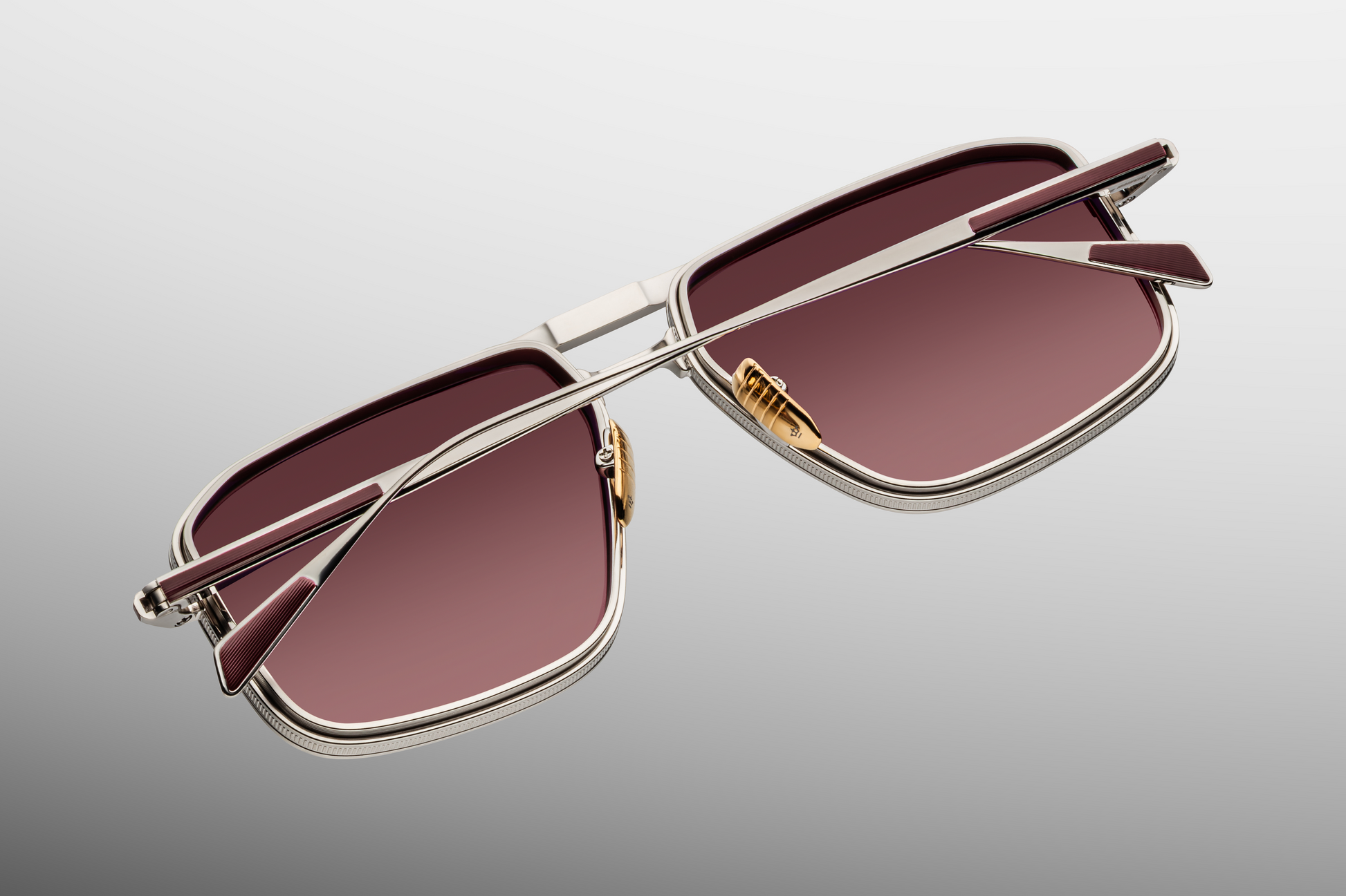Close-up of Earl Bordeaux temple showing silver hairline-engraved beta titanium structure, hidden tension-secured hinge, custom logo nose pad detail, and sleek acetate tips