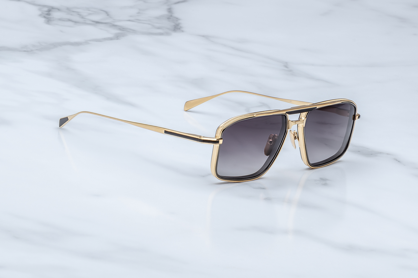Side close-up of Earl CIA temple showing dark-gold beta titanium structure, custom arrowhead monoblock hinge, engraved logo nose pad, and smooth black acetate eyerim tip.