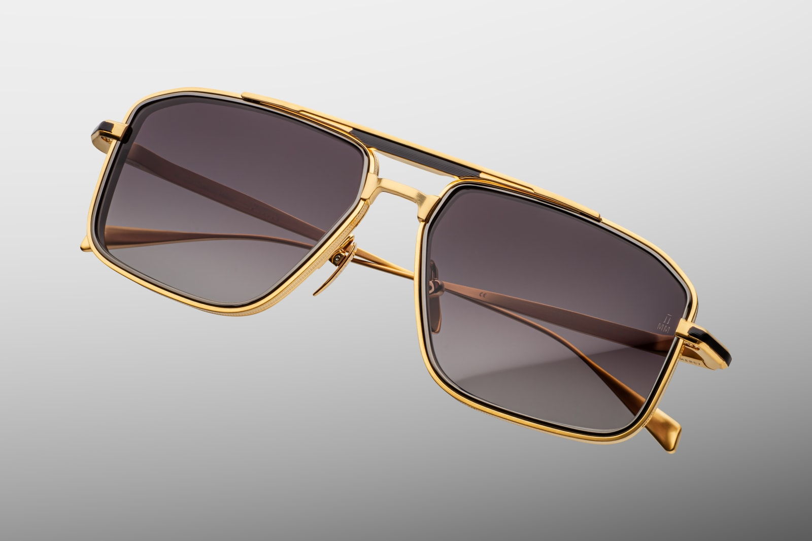 Three-quarter view of Earl CIA showcasing dual-tone dark-gold brow bar and black temple details, 4 mm titanium lens-rim inserts, hairline-engraved temples with wing tips, and hidden tension-secured hinge.