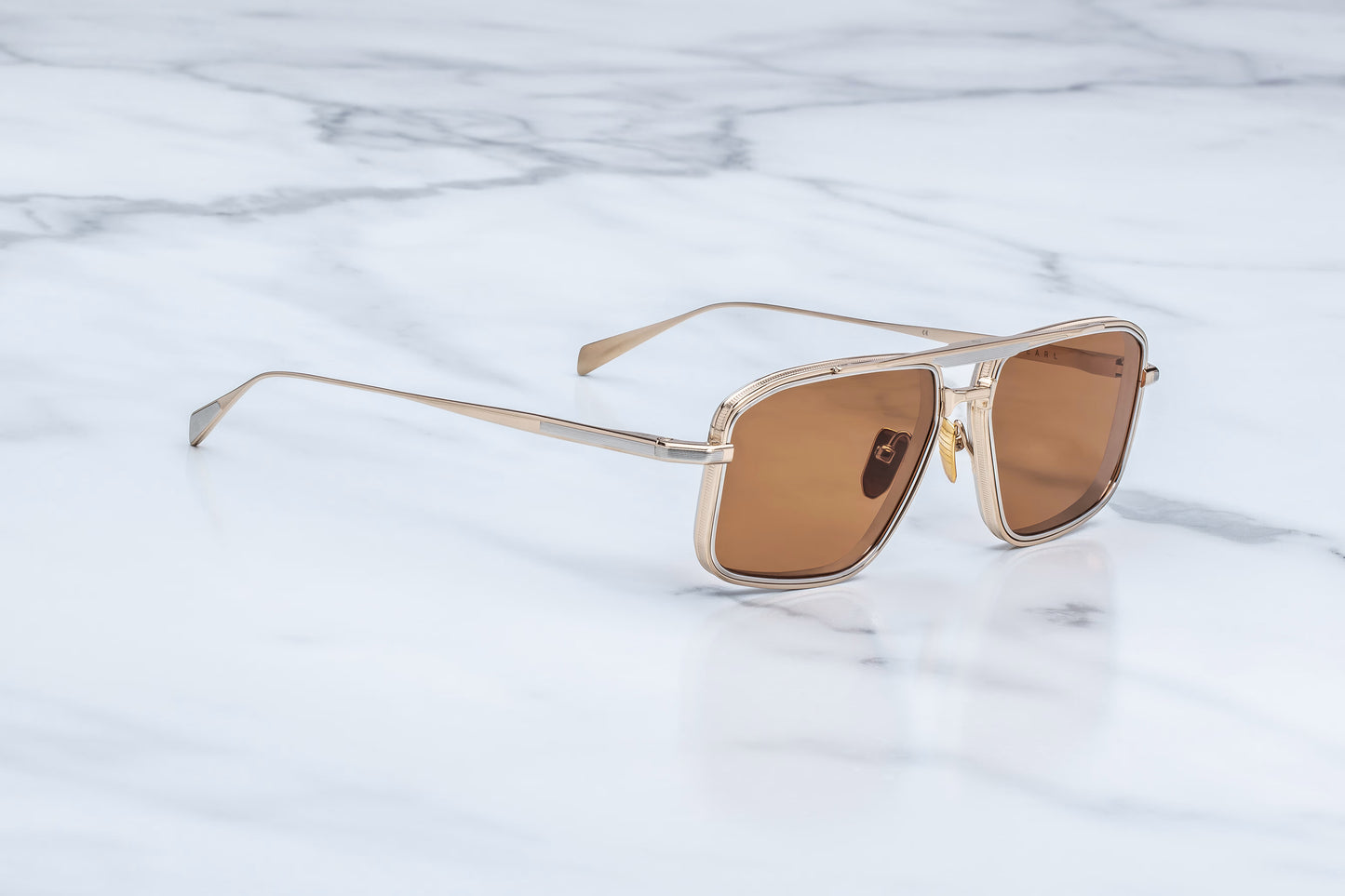 Three-quarter studio shot of the JMM Earl Darjeeling, highlighting the lightweight metal structure, unique 4mm thick titanium lens-rim inserts, and the fine Art Deco engravings on the frame corners.