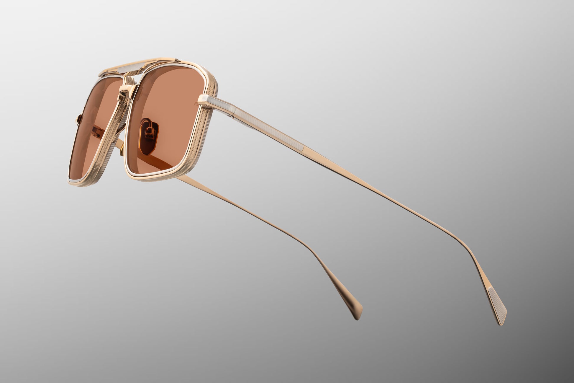 Side view of the JMM Earl sunglasses temple arm, showcasing the ultra-thin gold-finished beta titanium temple, custom hidden hinges, and the subtle silver palladium accents running along the metal wire.