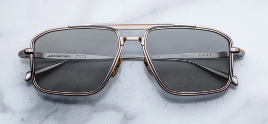 Front view of Jacques Marie Mage Earl sunglasses in Sweetheart, featuring a polished rose gold titanium navigator frame with dual-tone detailing and smoky ash grey lenses.
