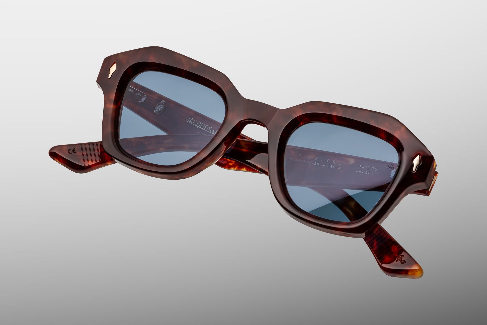 Close-up front detail of Jacques Marie Mage Eichler Breccia frame showing bevelled edges, gold arrowhead pins and polished brown acetate
Macro front view of JMM Eichler Breccia sunglasses highlighting geometric lens shape and handcrafted finish
