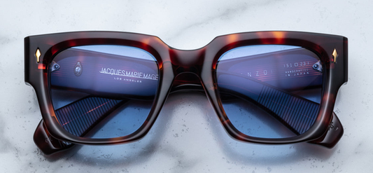 Jacques Marie Mage Enzo sunglasses in Havana—bold, oversized square frames handcrafted from 10mm double-laminated cellulose acetate. Features signature arrowhead front pins, polished metal wirecore temples, and custom 7-barrel hinges. Inspired by Enzo Ferrari's iconic style, these limited-edition sunglasses offer a commanding presence with a rich tortoiseshell finish