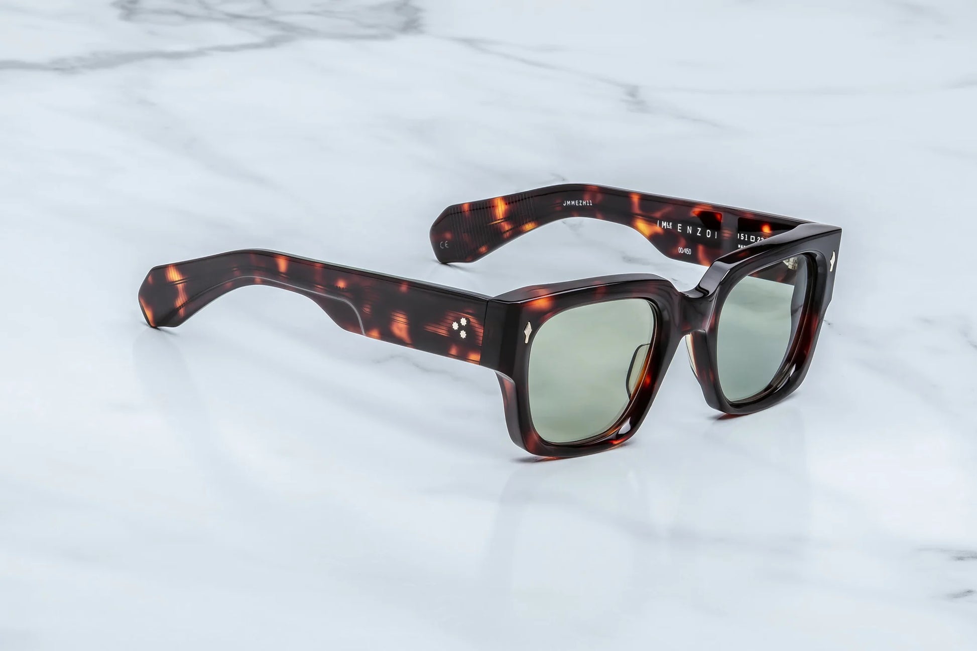 Three-quarter studio shot of the JMM Enzo Tenace sunglasses, highlighting the substantial 10mm thick sculpted frame, distinct beveled brow line, and rich amber-brown tortoise shell pattern.