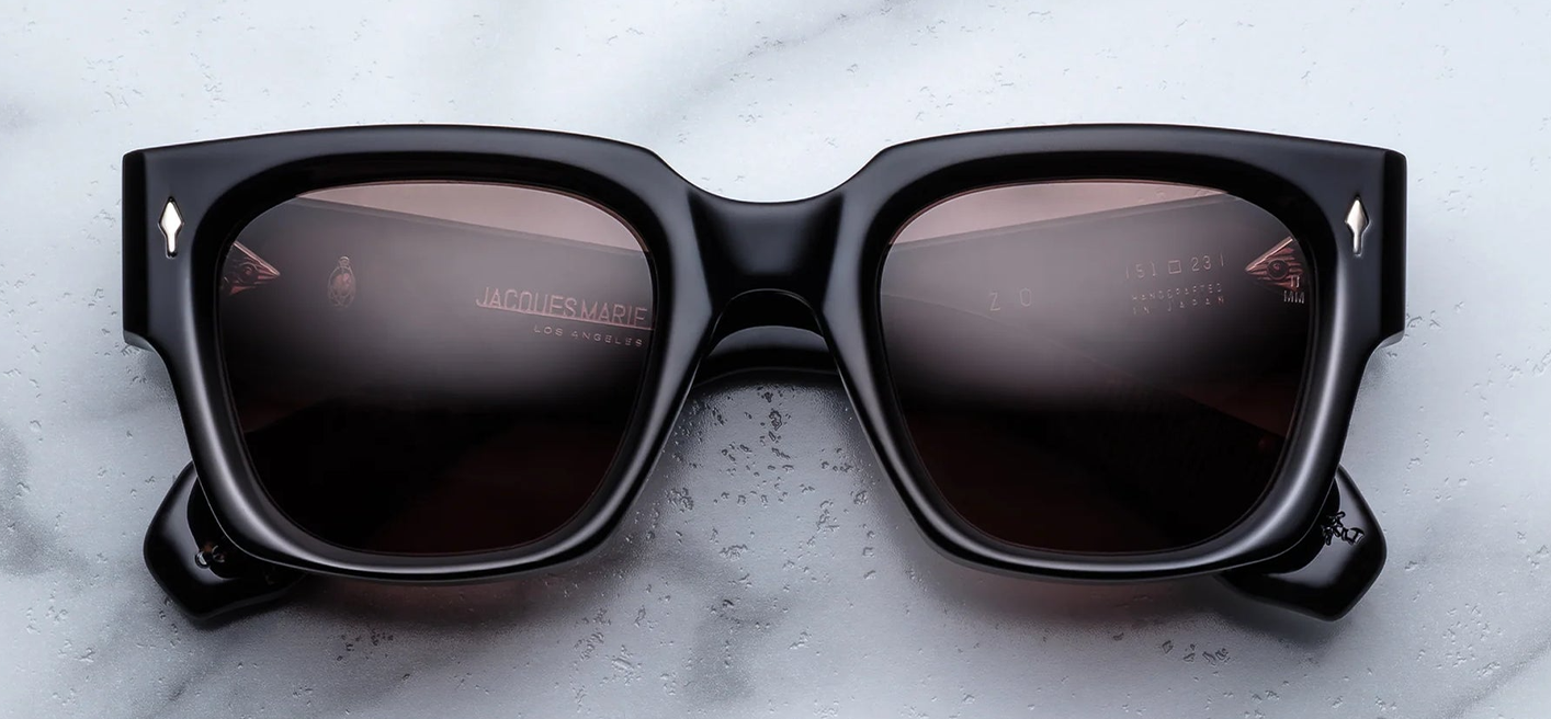 Front view of Jacques Marie Mage Enzo (Willow) sunglasses — bold black 10 mm cured cellulose‑acetate square frame with deep brown CR39 lenses and signature arrowhead front pins.