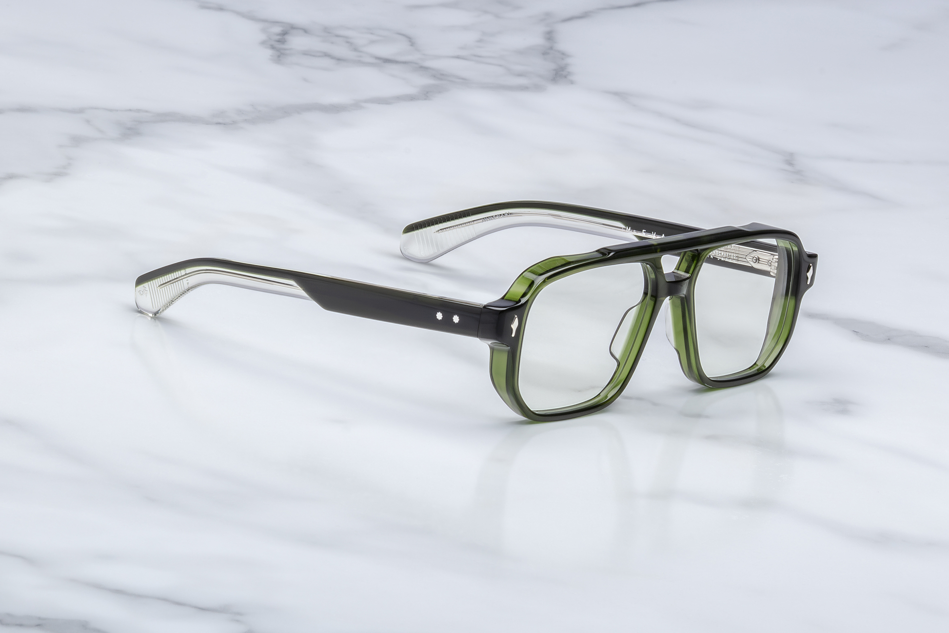 Side profile of Evans Borneo featuring custom double‑laminated green acetate temples, inner silver wirecore with filigree engraving, tension‑secured custom seven‑barrel hinge with sterling silver spur rivets, and domed 3D silver cameo logo