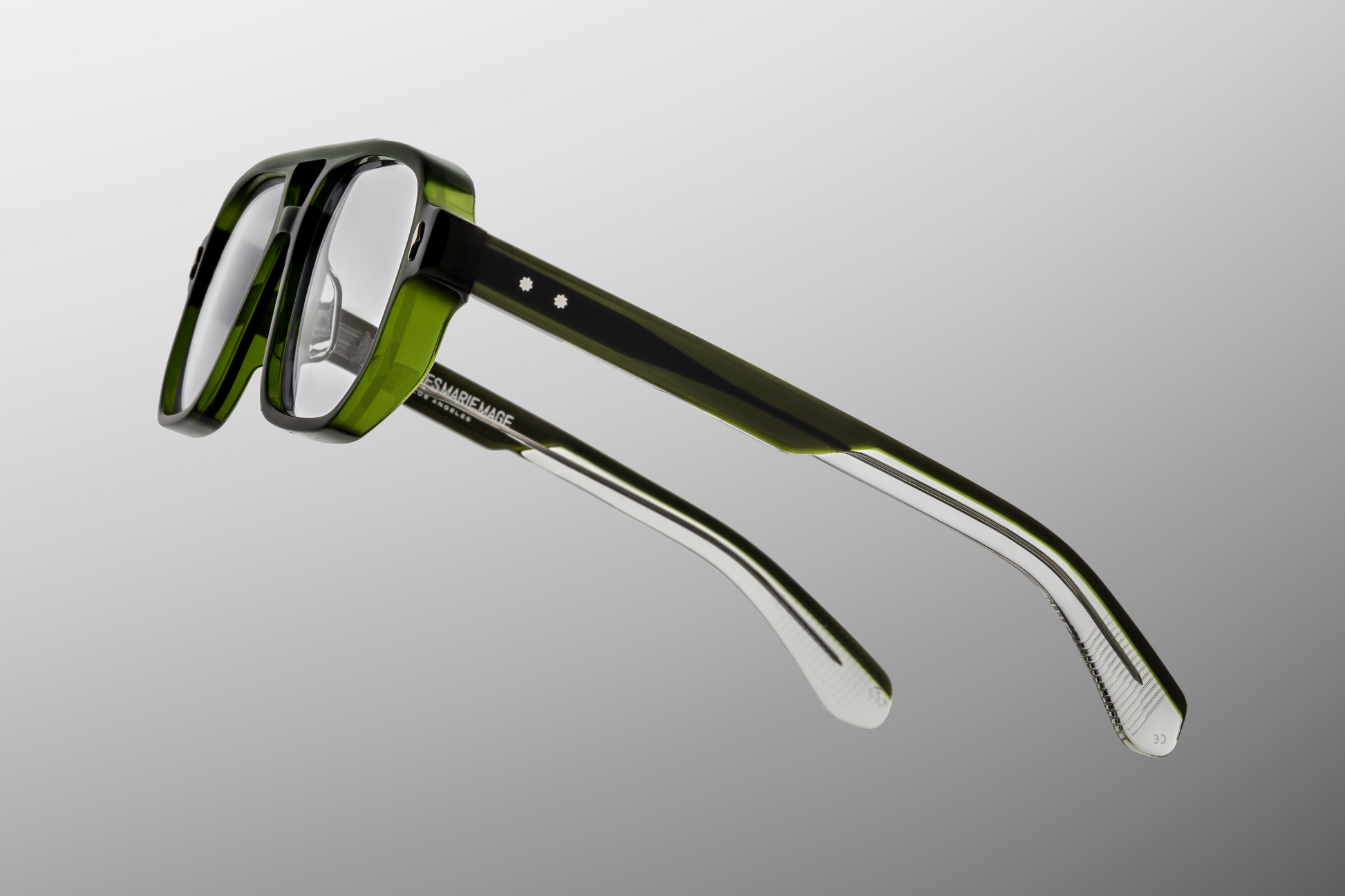 Side profile of Evans Borneo featuring custom double‑laminated green acetate temples, inner silver wirecore with filigree engraving, tension‑secured custom seven‑barrel hinge with sterling silver spur rivets, and domed 3D silver cameo logo