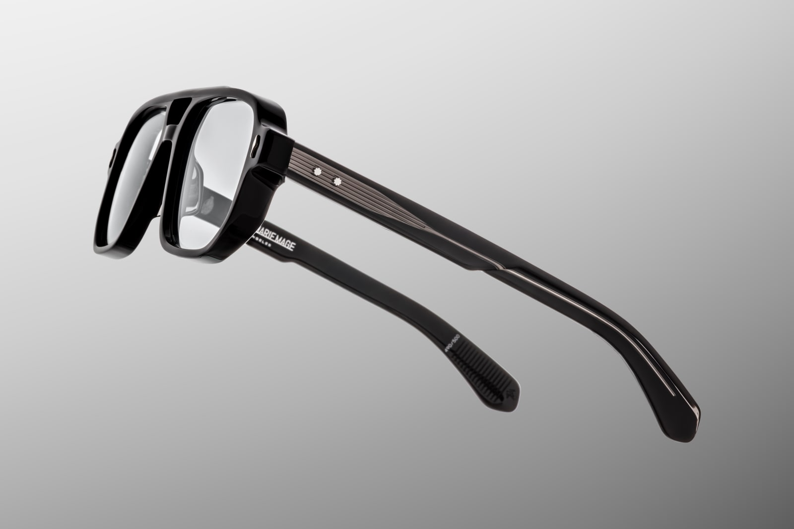 Side profile of Evans Raven showing custom double‑laminated acetate temples with exposed silver wirecore, tension‑secured 7‑barrel hinge adorned by spur‑shaped rivets, and a 3D metal cameo logo